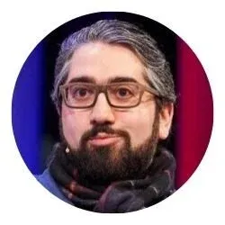 Man with glasses and a beard wearing a scarf in a circular frame.